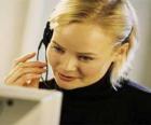 Trabajadora de telemarketing frente al ordenador con los cascos y el micrófono