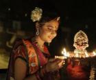 Mujer arrodillada con una lámpara de aceite en la mano en la celebración del Diwali