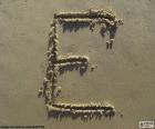 Letra "E" en mayúscula escrita en la arena de la playa
