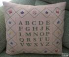 Cojín con el abecedario con letras mayúsculas, hecho en punto de cruz