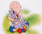 Caillou sentado en el suelo y abrazando a su gato Gilbert
