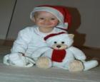 Niño con un gorro de Papá Noel junto a su osito de peluche