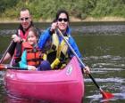 Familia, padre, madre, y hija, navegando y remando en una canoa, equipados con salvavidas