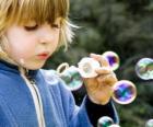 Niña jugando a hacer pompas de jabón o burbujas