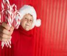 Niño con el gorro de Papá Noel y  bastoncitos de caramelo en la mano
