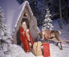 Papá Noel en la puerta de su casa junto a un reno y regalos