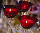 Tres velas encendidas en candelabros de cristal