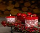 Velas  navideñas encendidas y decoradas con frutos rojos
