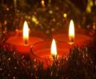 Tres velas de Navidad con la mecha ardiendo