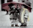 Niños paseando bajo la lluvia con su paraguas