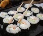 Comida japonesa con los palillos preparados, conocido como maki pues es sushi enrollado con alga