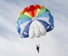 Paracaidista descendiendo entre las nubes en un paracaídas despues de saltar desde una avioneta