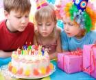 Niña en el momento de soplar las velas de su pastel de cumpleaños