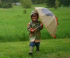 Niño con su paraguas y su chaqueta impermeable bajo la lluvia de primavera