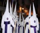 Nazarenos o penitentes durante una procesión de Semana Santa con capirote o cucurucho, túnica y capa