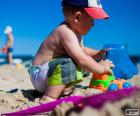 Un niño pequeño jugando con un camión en la playa 