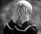 Un niño se esconde tapándose los ojos con sus manos
