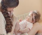 Mamá cogiendo las piernas de su bebé y con una mirada muy tierna