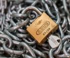 Cadena metálica y candado cerrado con su llave 