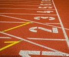 Linea de salida con ocho calles marcadas de una pista para la prueba atlética de 100 m 