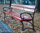 Banco de un parque con el suelo lleno de hojas secas en otoño
