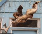 Ángel tocando una trompeta, colgado encima de la puerta de una casa