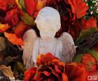 Ángel de piedra entre flores rojas