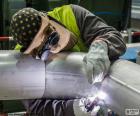 Soldador trabajando en la soldadura de una tubería, con todo el equipo de protección
