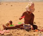 Una niña en verano jugando con la arena de la playa