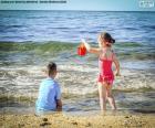 Un niño y una niña jugando en la playa un día de verano
