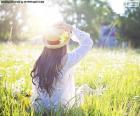 Mujer joven sentada en un campo lleno de flores en primavera