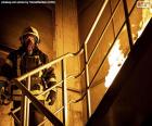 Bombero en una escalera ardiendo