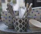 Bonita vajilla azul y blanca, con unos cubiertos dentro de una taza